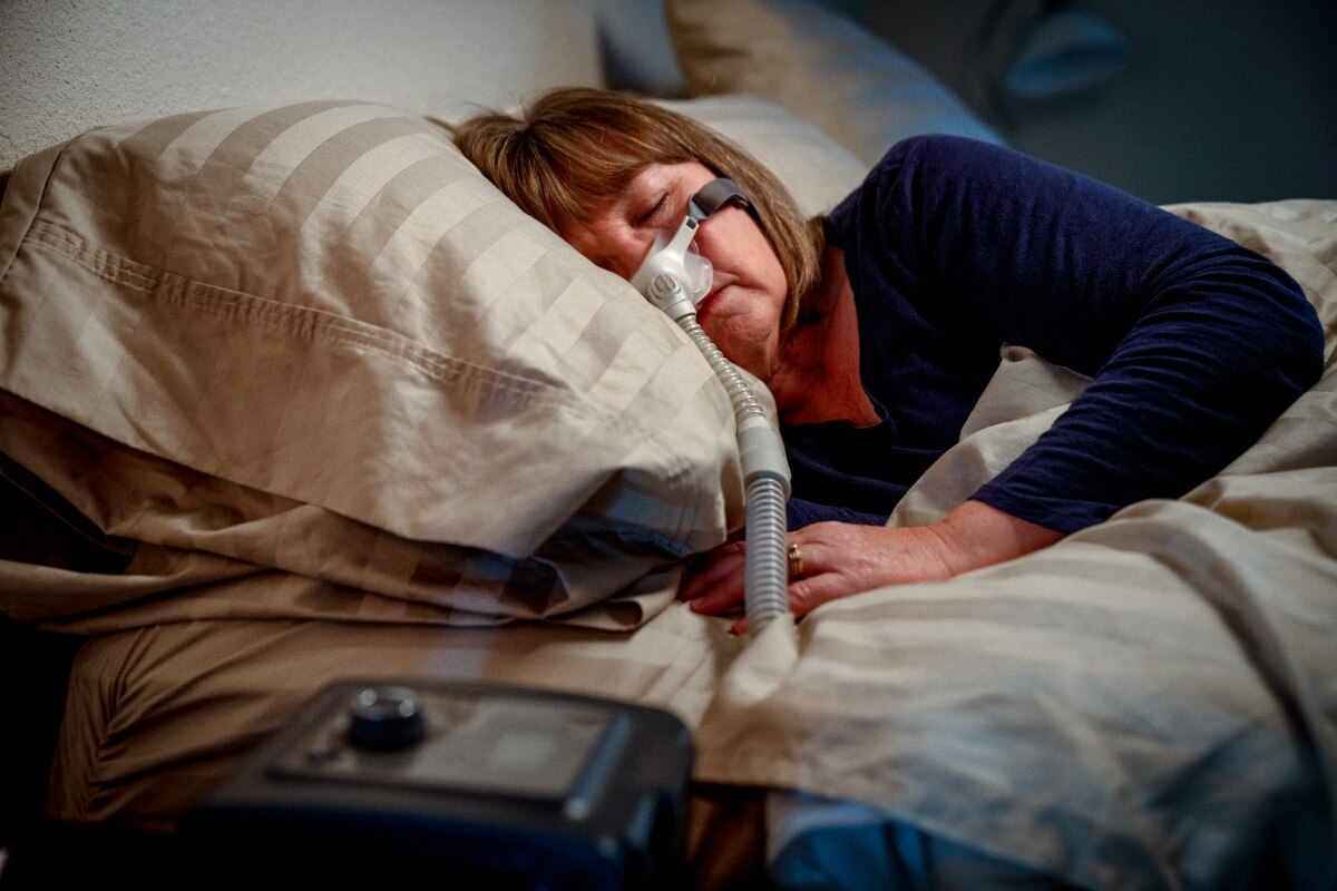Middle Aged Woman in her Fifties Sleeping Peacefully in Her Bed Using a CPAP Machine to Provide Therapy for Sleep Apnea